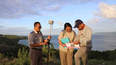 Petugas resmi BPN sedang mengukur tanah dengan dokumen dan identitas lengkap