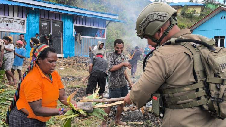 personel Satgas Damai Cartenz mengikuti tradisi bakar batu bersama warga di Sugapa Intan Jaya Papua dalam suasana kebersamaan